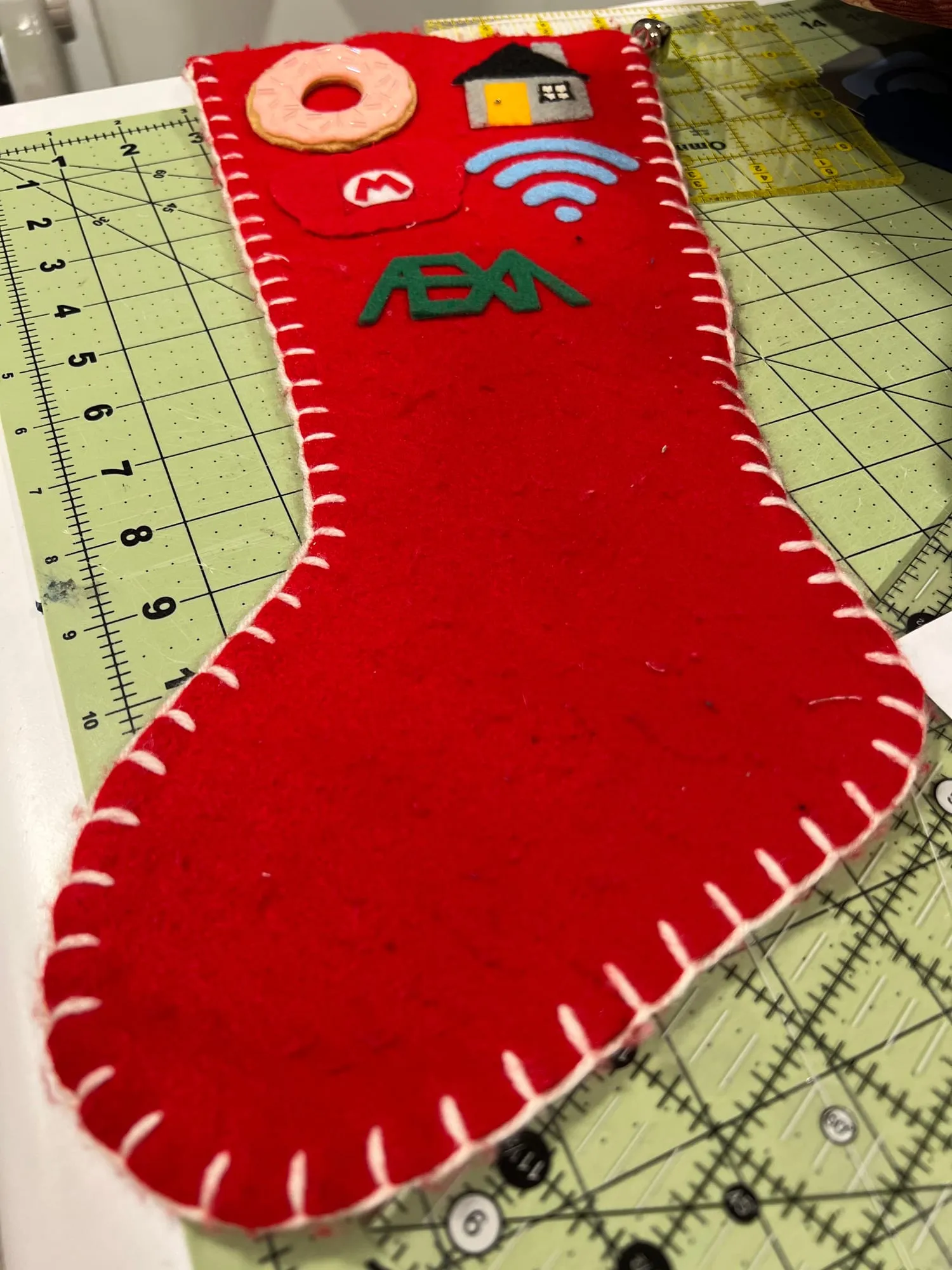 The back of the same stocking, plain red apart from a cluster at the top: a frosted donut, a small house, a wifi symbol and a green wordmark.