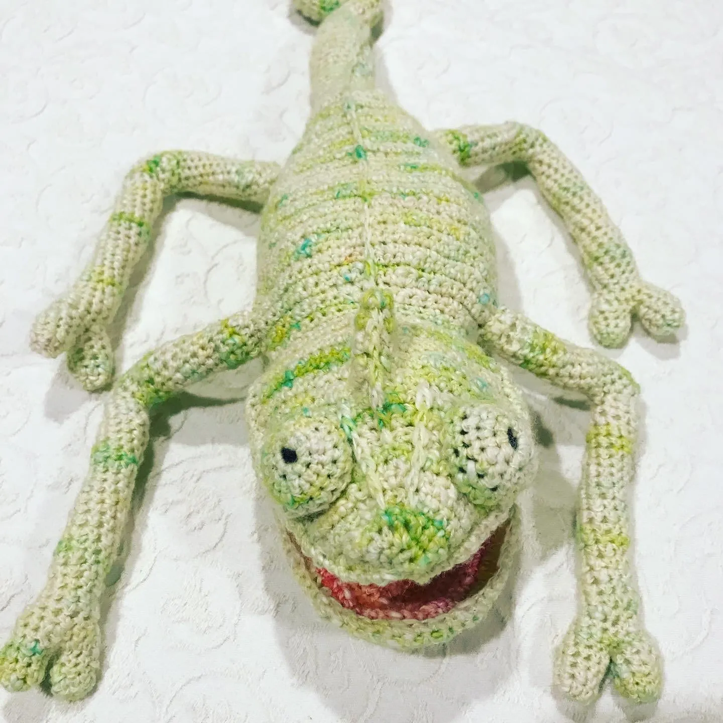 The same chameleon turned inside out, seen from above in variegated green, with splayed legs and a curled tail.