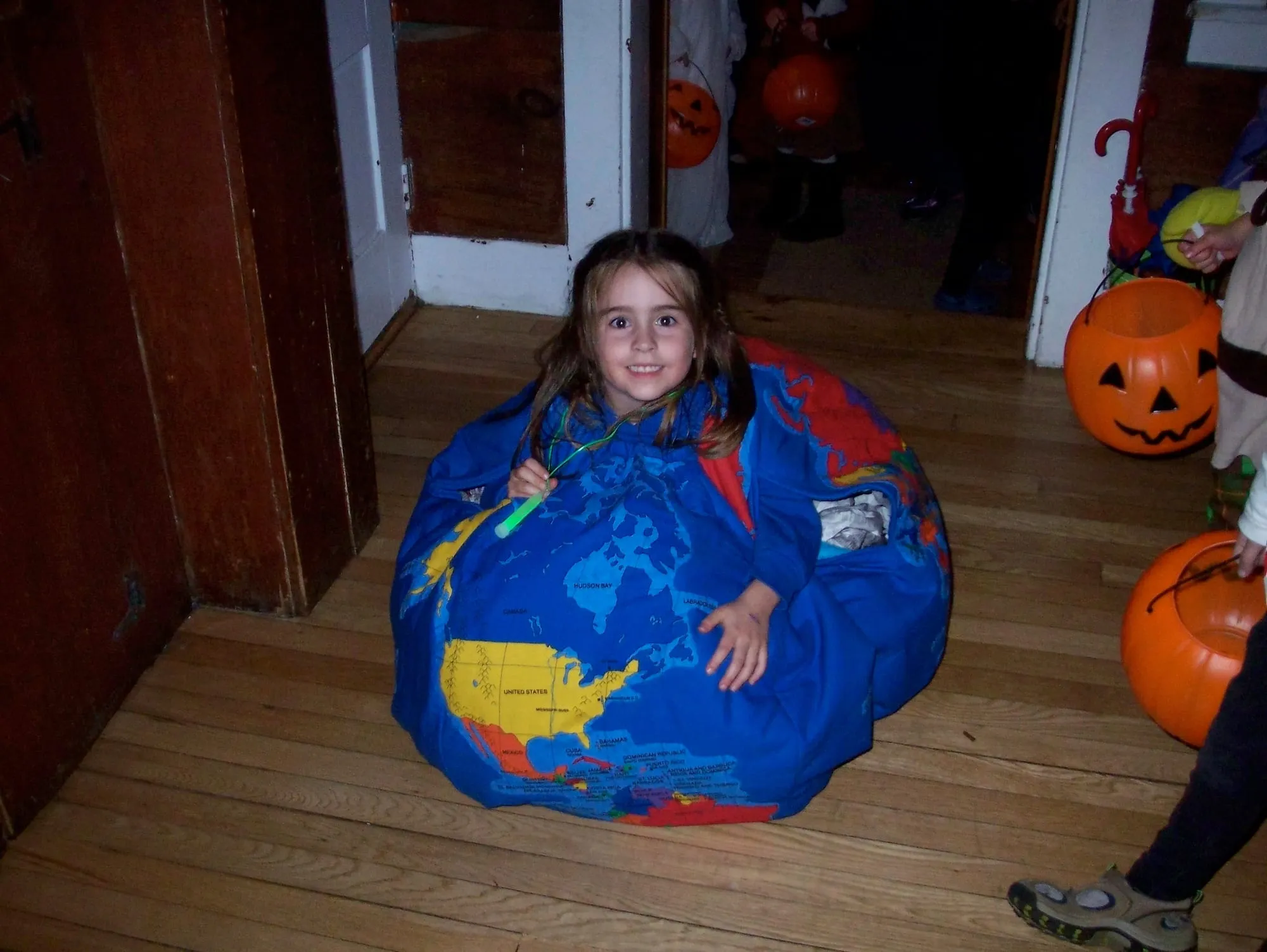 A child wearing a round stuffed and quilted costume made as a world map, showing North America and the Atlantic, worn over a long-sleeved top.