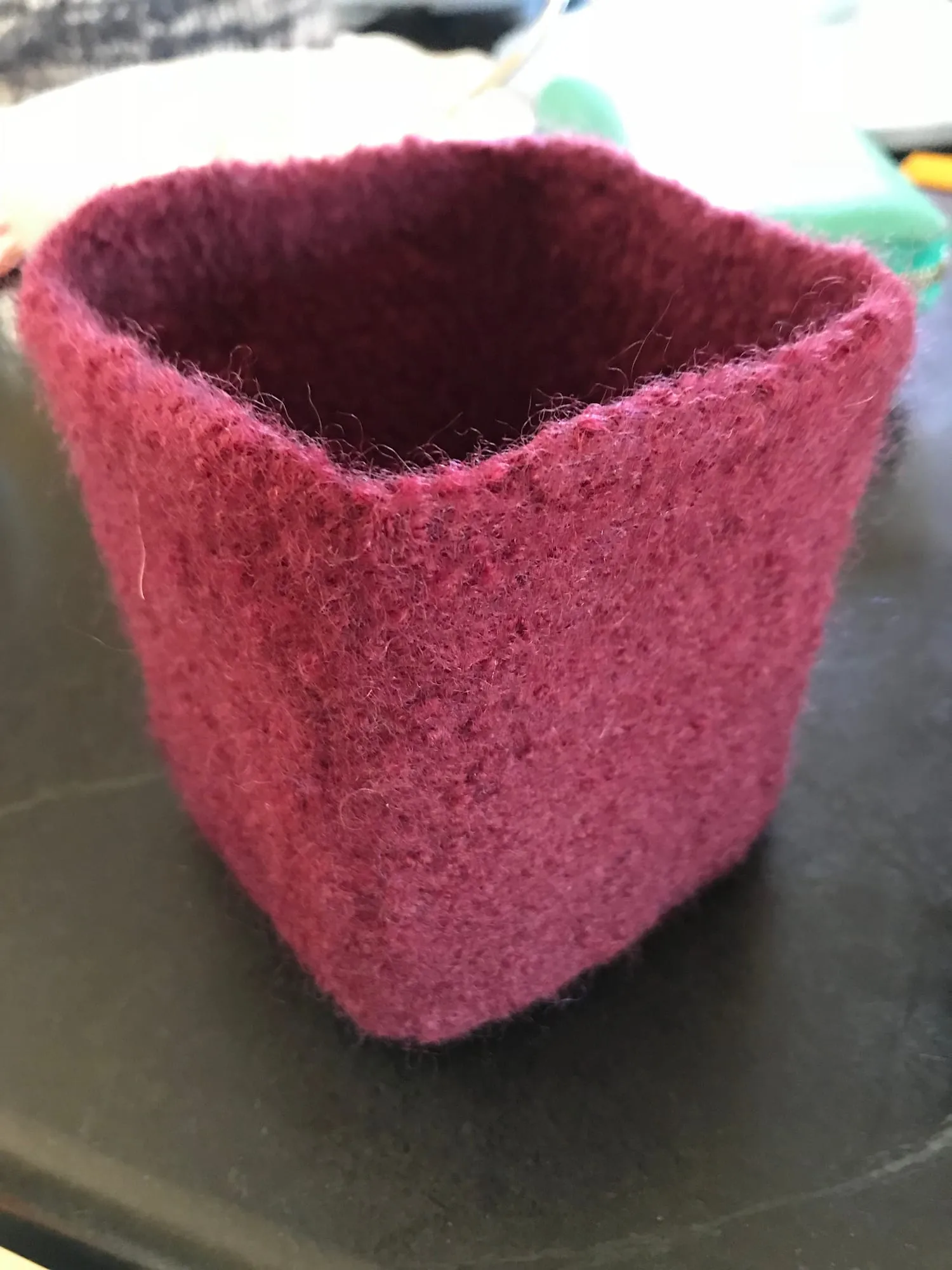 A square open-topped box in dark pink felted wool, holding its shape without a frame.